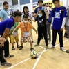 Các chuyên viên can thiệp hướng dẫn trẻ tự kỷ chơi bóng đá. (Ảnh: Đinh Hằng/TTXVN)