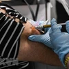 Nhân viên y tế tiêm thử nghiệm vắcxin ngừa COVID-19 trên tình nguyện viên. (Ảnh: AFP/TTXVN)