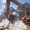 Lực lượng chức năng huyện Bảo Lâm dùng xe cơ giới phá hủy các bao phân bón trước khi chôn lấp để tiêu hủy hoàn toàn. (Ảnh: TTXVN phát)