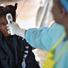 Nhân viên y tế kiểm tra thân nhiệt bệnh nhân nghi nhiễm virus Ebola tại Kenema, Guinea, ngày 16/8/2014. (Ảnh: AFP/TTXVN)