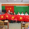 Đồn Biên phòng Tân Thành và UBND xã Tân Thành tặng cờ Tổ quốc cho 8 chủ phương tiện đã tham gia cứu hộ, cứu nạn. (Ảnh: Hữu Chí/TTXVN)