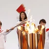 Vận động viên bóng đá Nhật Bản Azusa Iwashimizu (trái) thắp sáng ngọn đuốc Olympic tại lễ rước đuốc Olympic Tokyo 2020, ở Naraha, tỉnh Fukushima, Nhật Bản, ngày 25/3/2021. (Ảnh: AFP/TTXVN)