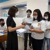 Thí sinh trình các giấy tờ và nộp bản khai báo y tế cho cán bộ coi thi tại điểm thi Trường Đại học Công nghệ Thành phố Hồ Chí Minh (cơ sở thành phố Thủ Đức). (Ảnh: Thu Hoài/TTXVN)