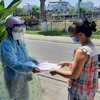 Đại diện chính quyền địa phương phát Thẻ đi chợ đến tận nhà cho các hộ dân quận Thanh Khê (Đà Nẵng). (Ảnh: TTXVN phát)