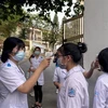 Các thí sinh tại điểm thi Trường Trung học phổ thông Bãi Cháy, thành phố Hạ Long được đo thân nhiệt, sát khuẩn tay ngay ở cổng trường. (Ảnh: TTXVN)