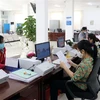 Cán bộ công chức Trung tâm Phục vụ hành chính công tỉnh Ninh Thuận giải quyết hồ sơ, thủ tục hành chính cho các doanh nghiệp. (Ảnh: Công Thử/TTXVN)