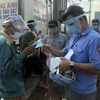 Trao tặng tấm chắn giọt bắn và khẩu trang cho người lao động tại cảng cá Quy Nhơn. (Ảnh: Nguyên Linh/TTXVN)