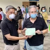 Thứ trưởng Bộ Y tế Nguyễn Trường Sơn (trái) trao giấy ra viện cho ông Piers Edmund Astley Birtwistle, 63 tuổi, người Anh (trú tại thành phố Thủ Đức, Thành phố Hồ Chí Minh) - một trong 17 bệnh nhân COVID-19 được xuất viện. (Ảnh: Hồng Giang/TTXVN)