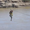 Người dân liều mình đu dây qua sông Pô Kô. (Ảnh: Khoa Chương/TTXVN)
