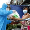 Tình nguyện viên chương trình 'Siêu thị 0 đồng di động' trao quà cho người lao động nghèo trên đường Hưng Phú, quận 8, Thành phố Hồ Chí Minh. (Ảnh: Thanh Vũ/TTXVN)