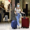 Hành khách đeo khẩu trang phòng lây nhiễm COVID-19 tại sân bay Heathrow, London, Anh. (Ảnh: AFP/TTXVN)