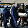 Người dân nhận thực phẩm cứu trợ của Hội Chữ thập Đỏ ở Kandahar, Afghanistan. (Ảnh: AFP/TTXVN)