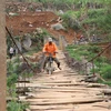 Người dân đi qua một cây cầu treo đã xuống cấp tại xã Chiềng Lương, huyện Mai Sơn. (Ảnh: Hữu Quyết/TTXVN)