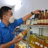 Anh Vũ Minh Ngọc kiểm tra sản phẩm giấm mơ trà xanh tại cửa hàng nông nghiệp sạch thành phố Nam Định. (Ảnh: Công Luật/TTXVN)