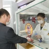 Khử khuẩn tay, đo thân nhiệt, nhằm ngăn chặn sự lây lan của dịch COVID-19 trước khi vào trung tâm thương mại ở Bình Nhưỡng, Triều Tiên. (Ảnh: AFP/TTXVN)