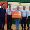 Bí thư Đảng ủy Khối các cơ quan Trung ương, ông Huỳnh Tấn Việt (thứ 2 từ trái) trao bảng tượng trưng 1 tỷ đồng hỗ trợ tỉnh Bình Định xây dựng 20 căn nhà cho hộ nghèo, chính sách. (Ảnh: Kha Phạm/TTXVN)