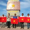 Đại diện lãnh đạo Cơ quan TTXVN khu vực phía Nam và lãnh đạo Công ty trách nhiệm hữu hạn một thành viên ITAXA tặng cờ Tổ quốc cho ngư dân tại Phú Quý. (Ảnh: Nguyễn Thanh/TTXVN)