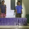 Đối tượng Nguyễn Văn Đoàn và Võ Thanh Thành bị Đồn Biên phòng Vàm Trảng Trâu bắt giữ khi vận chuyển 2.000 gói thuốc lá lậu. (Ảnh: TTXVN phát)