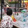 Nhân viên y tế lấy mẫu xét nghiệm COVID-19 cho người dân tại Quảng Châu, Trung Quốc. (Ảnh: AFP/TTXVN)