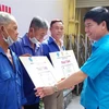 Ông Phạm Chí Tâm, Phó Chủ tịch Liên đoàn Lao động Thành phố Hồ Chí Minh trao tặng thẻ bảo hiểm y tế cho người lao động có hoàn cảnh khó khăn. (Ảnh: Thanh Vũ/TTXVN)