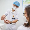 Nhân viên y tế hướng dẫn người dân trước khi tiêm vaccine. (Ảnh: PV/Vietnam+)