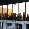 Các đại biểu thử nghiệm hệ thống bắn súng mô phỏng tại trường bắn điện tử. (Nguồn: Công an nhân dân)