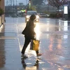Người dân di chuyển trên đường phố dưới trời mưa bão ở Mỹ. (Ảnh: THX/TTXVN)