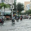 Người dân di chuyển giữa làn nước trên đường Huỳnh Tấn Phát ở quận 7. (Ảnh: Hồng Giang/TTXVN)