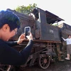 Người dân chụp ảnh tại đầu máy xe lửa hơi nước Tự Lực được trưng bày trong khuôn khổ Lễ hội Thiết kế Sáng tạo Hà Nội 2023. (Ảnh: Tuấn Đức/TTXVN)
