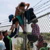 Người di cư trèo qua hàng rào từ Mexico vào Mỹ tại Eagle Pass, bang Texas (Mỹ) ngày 25/8/2023. (Ảnh: AFP/TTXVN)
