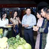 Các quan khách và người dân địa phương ăn thử các loại hoa quả do một doanh nghiệp Việt Nam trồng tại khu vực Tam giác Phát triển CLV. (Ảnh: Phạm Kiên/TTXVN)