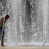 Người dân làm mát tại một đài phun nước ở Seville, Tây Ban Nha. (Ảnh: AFP/TTXVN)