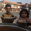 Trẻ em nhận thức ăn cứu trợ tại thành phố Khan Younis, Dải Gaza. (Ảnh: THX/TTXVN)