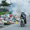 Người dân đi qua khu vực bãi rác lộ thiên này tỏ ra vô cùng khó chịu (Ảnh: Minh Sơn/Vietnam+) 