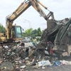 Công nhân vệ sinh môi trường tiến hành dọn dẹp bãi rác tại xã Tân Triều sáng 10/7. (Ảnh: Sơn Bách/Vietnam+) 