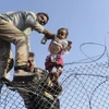 Người di cư Syria cố vượt qua hàng rào dây thép gai để vào lãnh thổ Thổ Nhĩ Kỳ ngày 14/6. (Nguồn: AFP/TTXVN)