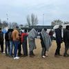 Dòng người di cư và tị nạn nhận lương thực, thực phẩm trong khi chờ đợi được qua cửa khẩu Hy Lạp-Macedonia, gần Idomeni (Hy Lạp) ngày 20/1. (Nguồn: AFP/TTXVN)