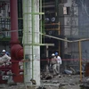 Các công nhân tìm kiếm nạn nhân mất tích trong vụ nổ tại nhà máy hóa dầu Pajaritos. (Nguồn: AFP/TTXVN)