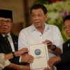 Tổng thống Rodrigo Duterte (giữa) và đại diện của MILF giơ cao dự luật mang tên “Luật Cơ bản Bangsamoro” tại buổi lễ ở Manila. (Nguồn: AFP/TTXVN)