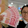 Nhân viên ngân hàng Trung Quốc giới thiệu đồng 100 nhân dân tệ thiết kế mới tại Handan, tỉnh Hà Bắc. (Nguồn: AFP/TTXVN)