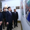 Phó Thủ tướng Vương Đình Huệ (giữa), Tổng Giám đốc Thông tấn xã Việt Nam Nguyễn Đức Lợi (trái) cùng các đại biểu tham quan triển lãm. (Ảnh: Quang Quyết/TTXVN)