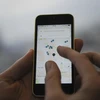 Một khách hàng sử dụng điện thoại di động để gọi dịch vụ xe của Uber . (Nguồn: AFP/TTXVN)