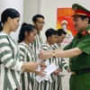 Đại tá Nguyễn Văn Viện, Phó Giám đốc Công an Thành phố Hà Nội trao Quyết định của Tòa án nhân dân thành phố về việc tha tù trước thời hạn có điều kiện cho các phạm nhân. (Ảnh: TTXVN phát)