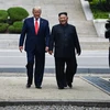 Tổng thống Mỹ Donald Trump (trái) và nhà lãnh đạo Triều Tiên Kim Jong-un (giữa) trong cuộc gặp tại Khu phi quân sự (DMZ) ở biên giới liên Triều chiều 30/6/2019. (Ảnh: AFP/TTXVN)