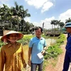 Anh Trung Kiên con trai bà Nguyễn Thị Hoa ( áo xanh ở giữa) trao đổi về việc mẹ hiến căn nhà và đất cho chính quyền cải tạo suối Đồng Tiền. (Ảnh: Dương Chí Tưởng/TTXVN)