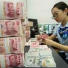 Kiểm đồng 100 nhân dân tệ tại ngân hàng ở tỉnh Giang Tô, Trung Quốc. (Ảnh: AFP/TTXVN)