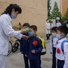 Đo thân nhiệt phòng lây nhiễm dịch COVID-19 tại một trường học ở Bình Nhưỡng, Triều Tiên. (Ảnh: AFP/TTXVN)