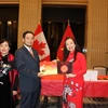 Giáo sư Julie Nguyễn (áo đỏ) tặng Đại sứ Việt Nam tại Canada Phạm Cao Phong và phu nhân hai tác phẩm "Bài ca Hồ Chí Minh" và "Lời ru nước Việt" mà giáo sư vừa ra mắt. (Ảnh: Vũ Quang Thịnh/TTXVN)