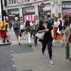 Người dân di chuyển trên đường phố tại London, Anh. (Ảnh: AFP/TTXVN)