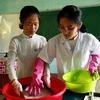 Hai nữ sinh thực hiện công đoạn sản xuất giấy theo phương pháp thủ công trong phòng thí nghiệm.